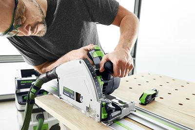 Vyras su „Festool“ diskiniu pjūklu pjauna lentą ant daugiafunkcio stalo