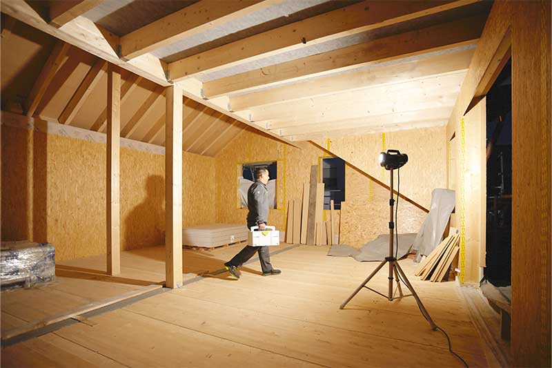 Statybinis šviestuvas apšviečia tamsų kambarį be langų