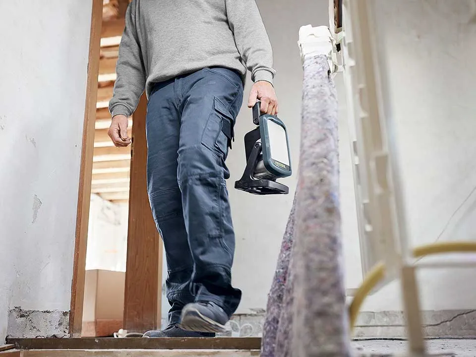 Amatininkas neša statybinį šviestuvą