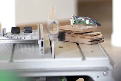 Pasiruošimas darbui: Festool PRECISIO CS 50 stalo pjūklas ir ant jo padėti apsauginiai akiniai